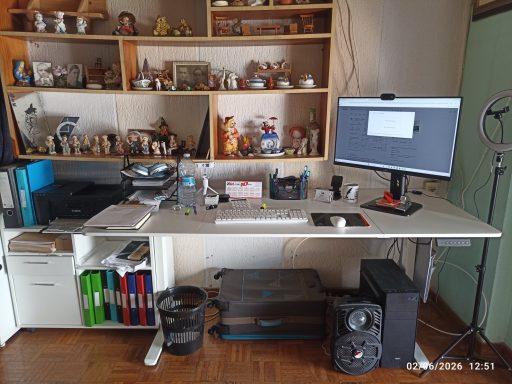 Mi despacho Escritorio moderno con computadora, estanterías llenas de objetos y altavoces.